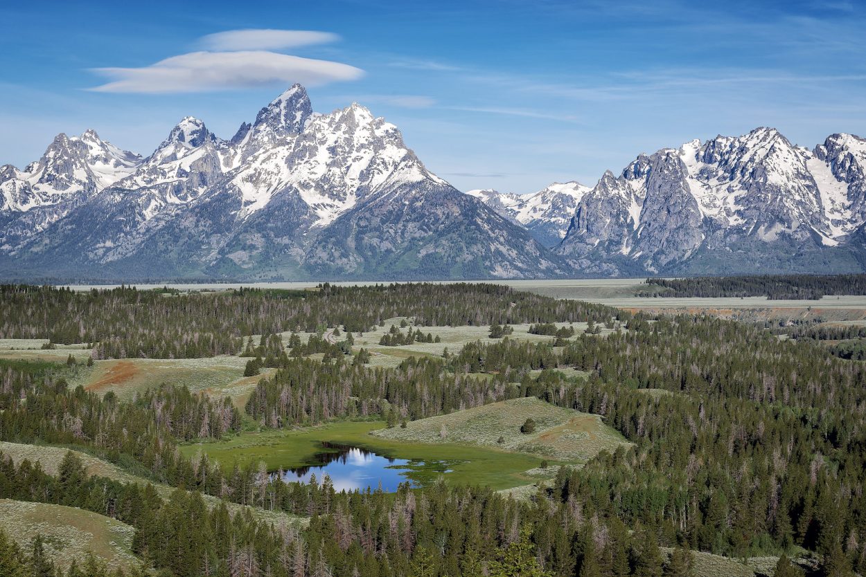 Grand Teton National Park is a United States National Park in northwestern Wyoming. At approximately 310,000 acres (480 sq mi; 130,000 ha; 1,300 km2), the park includes the major peaks of the 40-mile-long (64 km) Teton Range as well as most of the northern sections of the valley known as Jackson Hole. It is only 10 miles (16 km) south of Yellowstone National Park, to which it is connected by the National Park Service-managed John D. Rockefeller, Jr. Memorial Parkway. Along with surrounding National Forests, these three protected areas constitute the almost 18,000,000-acre (7,300,000 ha) Greater Yellowstone Ecosystem, one of the largest intact mid-latitude temperate ecosystems in the world. Human history of the Grand Teton region dates back at least 11,000 years, when the first nomadic hunter-gatherer Paleo-Indians began migrating into the region during warmer months pursuing food and supplies. In the early 19th century, the first White explorers encountered the eastern Shoshone natives. Between 1810 and 1840, the region attracted fur trading companies that vied for control of the lucrative beaver pelt trade. U.S. Government expeditions to the region commenced in the mid-19th century as an offshoot of exploration in Yellowstone, with the first permanent white settlers in Jackson Hole arriving in the 1880s. Efforts to preserve the region as a national park commenced in the late 19th century, and in 1929 Grand Teton National Park was established, protecting the major peaks of the Teton Range. The valley of Jackson Hole remained in private ownership until the 1930s, when conservationists led by John D. Rockefeller, Jr. began purchasing land in Jackson Hole to be added to the existing national park. Against public opinion and with repeated Congressional efforts to repeal the measures, much of Jackson Hole was set aside for protection as Jackson Hole National Monument in 1943. The monument was abolished in 1950 and most of the monument land was added to Grand Teton National Park. Grand Teton National Park is named for Grand Teton, the tallest mountain in the Teton Range. The naming of the mountains is attributed to early 19th-century French-speaking trappers—les trois tétons (the three teats) was later anglicized and shortened to Tetons. At 13,775 feet (4,199 m), Grand Teton abruptly rises more than 7,000 feet (2,100 m) above Jackson Hole, almost 850 feet (260 m) higher than Mount Owen, the second-highest summit in the range. The park has numerous lakes, including 15-mile-long (24 km) Jackson Lake as well as streams of varying length and the upper main stem of the Snake River. Though in a state of recession, a dozen small glaciers persist at the higher elevations near the highest peaks in the range. Some of the rocks in the park are the oldest found in any U.S. National Park and have been dated at nearly 2.7 billion years. Grand Teton National Park is an almost pristine ecosystem and the same species of flora and fauna that have existed since prehistoric times can still be found there. More than 1,000 species of vascular plants, dozens of species of mammals, 300 species of birds, more than a dozen fish species and a few species of reptiles and amphibians exist. Due to various changes in the ecosystem, some of them human-induced, efforts have been made to provide enhanced protection to some species of native fish and the increasingly threatened whitebark pine. Grand Teton National Park is a popular destination for mountaineering, hiking, fishing and other forms of recreation. There are more than 1,000 drive-in campsites and over 200 miles (320 km) of hiking trails that provide access to backcountry camping areas. Noted for world-renowned trout fishing, the park is one of the few places to catch Snake River fine-spotted cutthroat trout. Grand Teton has several National Park Service-run visitor centers, and privately operated concessions for motels, lodges, gas stations and marinas.

[source: en.wikipedia.org/wiki/Grand_Teton_National_Park]

Website: www.nps.gov/grte/index.htm