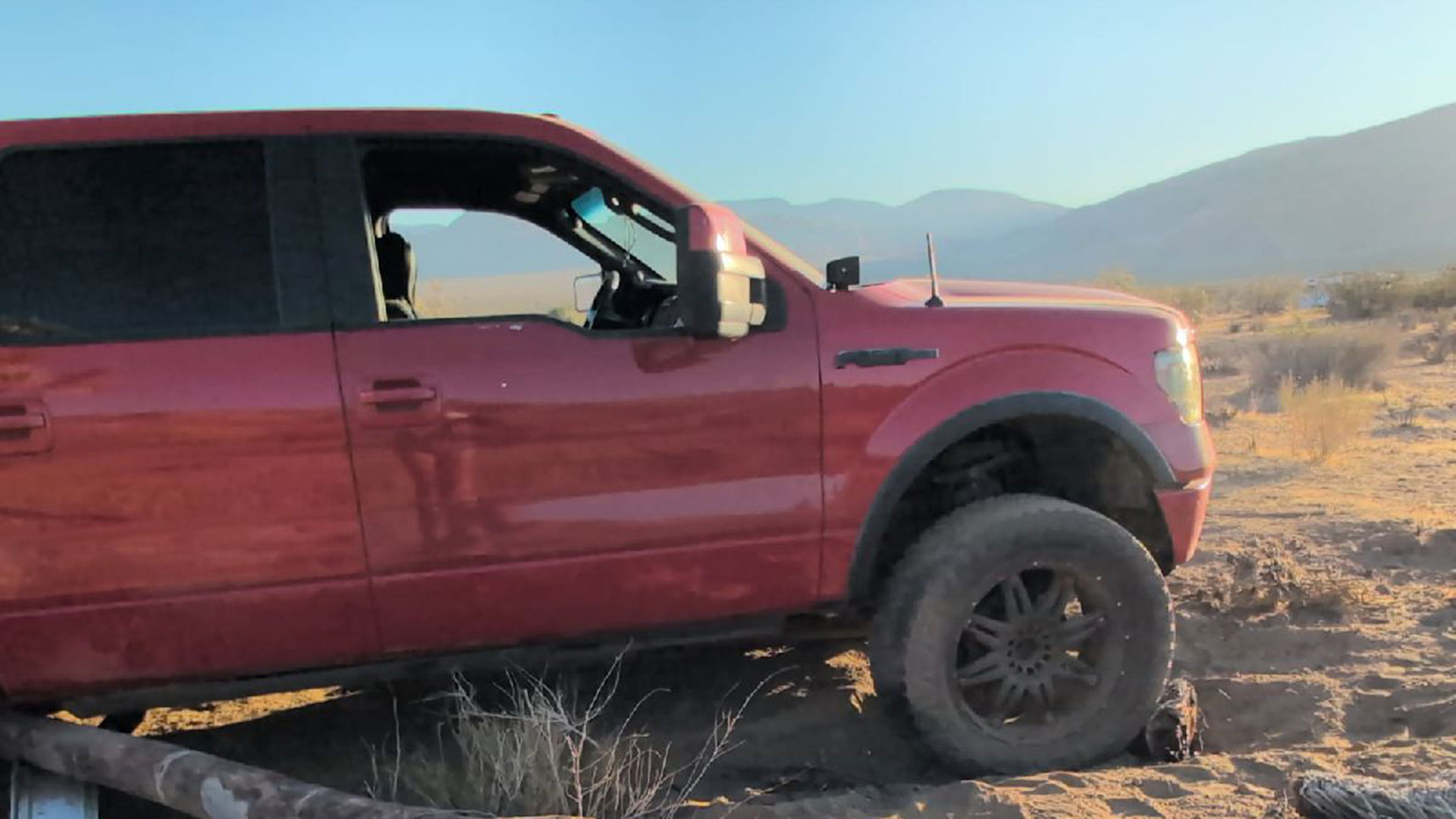 Red 4×4 Ford pickup stuck over a log Red 4×4 Ford pickup stuck over a log